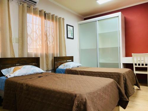two beds in a room with red walls and a window at Dollosa Compound in Iba