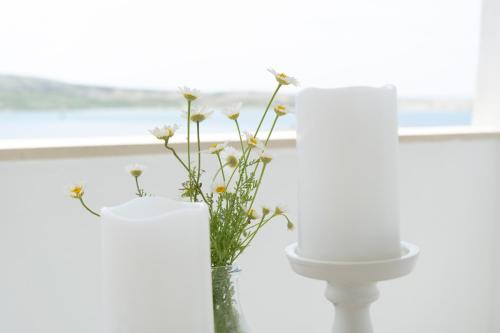 a white bathroom with a toilet and a vase with flowers at L'infini Sea View apartments Zubovići in Zubovići