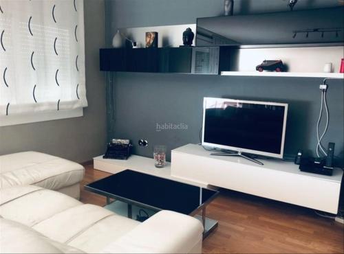 a living room with a white couch and a television at Piso Jùlia in Mataró