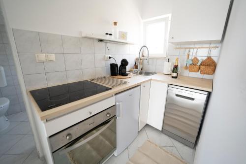 a white kitchen with a sink and a dishwasher at L'infini Sea View apartments Zubovići in Zubovići
