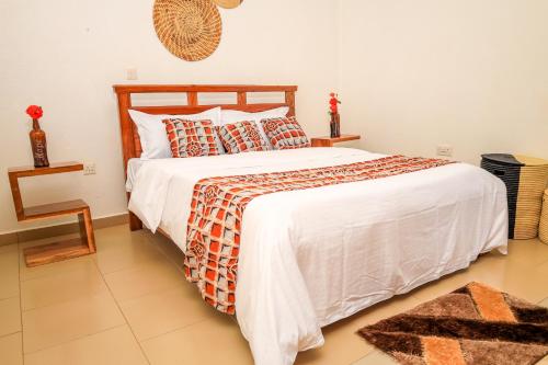 a bedroom with a bed with a white bedspread at Stee's Cottages in Mukono