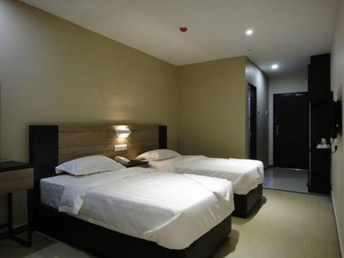 a hotel room with two beds with white sheets at Galaxy Hotel SIMPANG AMPAT in Simpang Ampat
