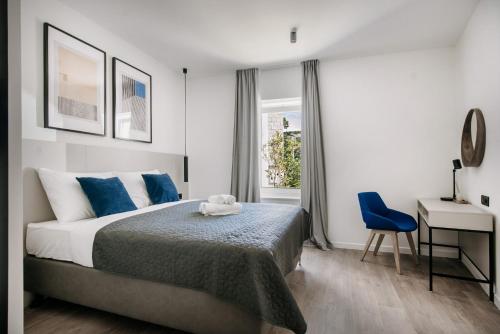 a bedroom with a bed and a desk with a blue chair at KALA LUXURY ROOMS by DuHomes in Dubrovnik