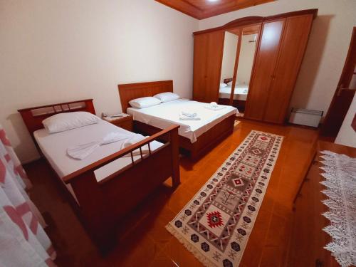 two beds in a small room with a rug at Sokolli Guest House in Gjirokastër
