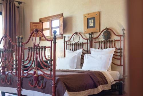 a bedroom with a large wooden bed with white pillows at Jnane Allia in Douar Soukkane