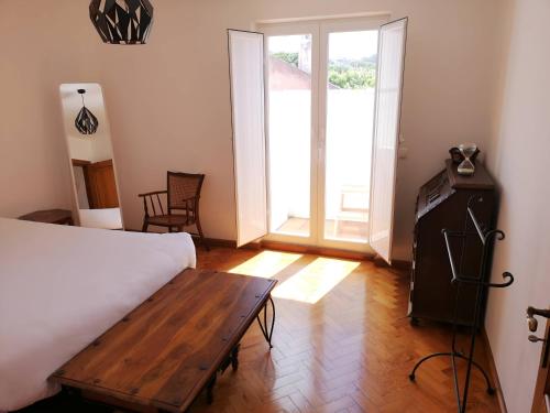 Schlafzimmer mit einem Bett, einem Tisch und einem Fenster in der Unterkunft Casa Mateus - Colares, Parque Natural Sintra Cascais in Sintra