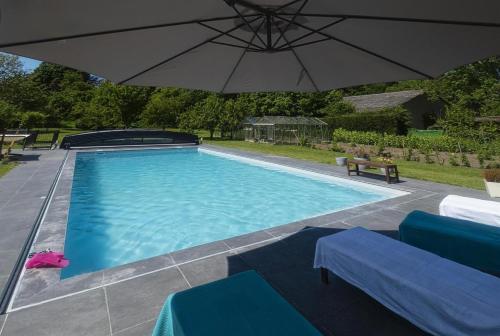 ein großer Swimmingpool mit Sonnenschirm und Stühlen in der Unterkunft Le Logis Du Regisseur Gite in Charny