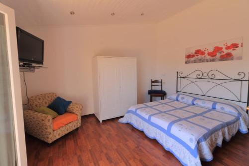 a bedroom with a bed and a chair and a flat screen tv at B&b SAN LORENZO in Conversano
