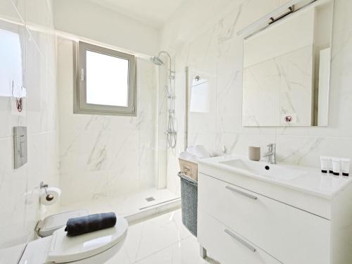 a white bathroom with a toilet and a sink at Costa Alimos by Verde Apartments in Athens