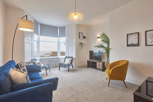 a living room with a blue couch and chairs and a tv at 5 Roker Terrace - Seaview Apartments in Sunderland
