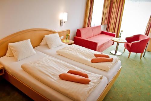 una habitación de hotel con 2 camas y una silla en Der Thomashof en Sankt Jakob im Rosental