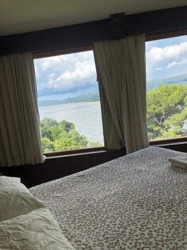 a bedroom with a bed and two large windows at casas lago in Villa Carlos Paz