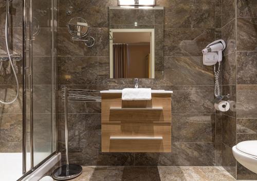 a bathroom with a sink and a shower at Hôtel Spa Thermalia in Châtel-Guyon