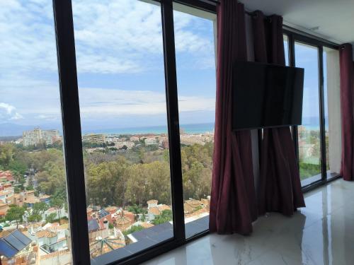 a room with a view of a city through windows at Pinar Suites Loft in Torremolinos
