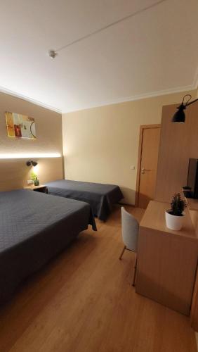 a hotel room with two beds and a table and a chair at Ferrinho in Guarda