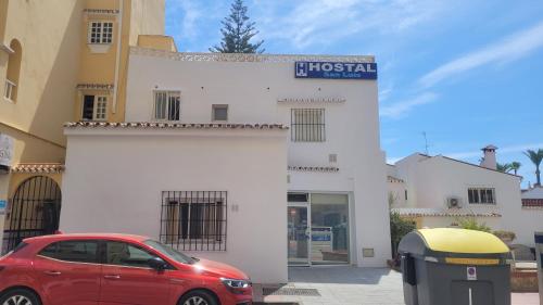 a red car parked in front of a building at Hostal San Luis in San Luis de Sabinillas
