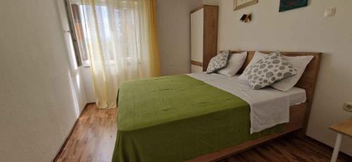 a bedroom with a green bed and a window at Apartment Vrbnik 2 in Vrbnik
