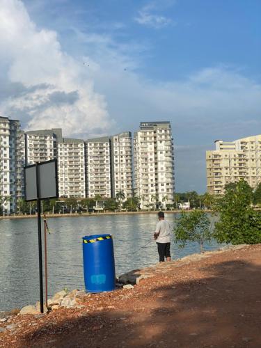 a man standing next to a body of water with buildings at Marina Terrace A1-10 in Port Dickson