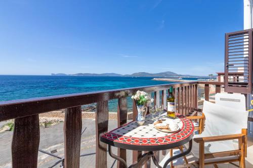 a table on a balcony with a view of the ocean at Alguerhome Casa Blu sea view in Alghero