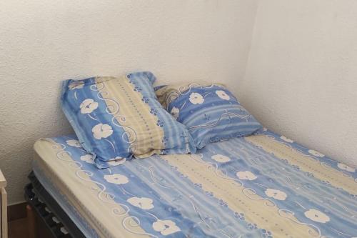 - un lit avec une couette et des oreillers bleus dans l'établissement Petit appart sympa clim piscine balcon, à Gruissan