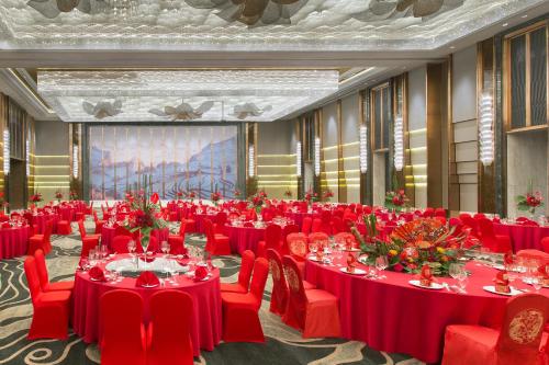a banquet hall with red tables and chairs and a screen at Wanda Vista Nanning in Nanning