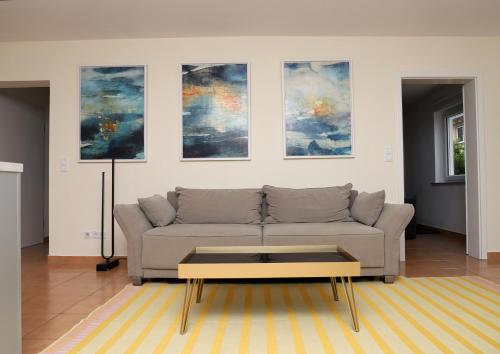 a living room with a couch and paintings on the wall at Art & Nature Apartments in der Nähe FFM-Messe in Bad Vilbel