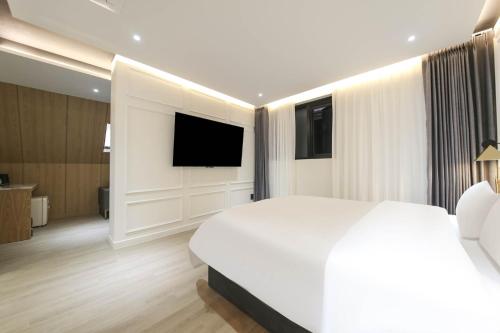 a bedroom with a large white bed and a flat screen tv at Brown Dot Hotel Pyeonghwa plaza in Mokpo