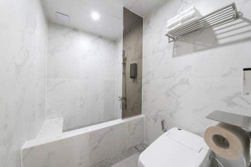 a white bathroom with a toilet and a shower at Brown Dot Hotel Pyeonghwa plaza in Mokpo