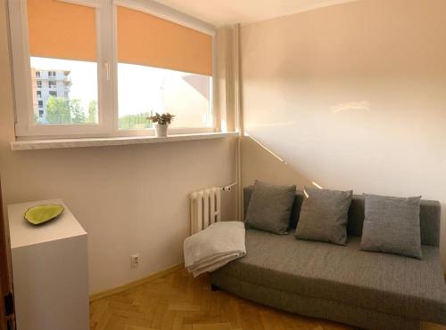 a room with a couch with pillows and a window at Park Regana in Gdańsk