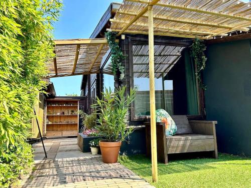 a pergola on a house with a bench and plants at Jungle style lodge with jacuzzi ,sauna and garden near Amsterdam in Vijfhuizen