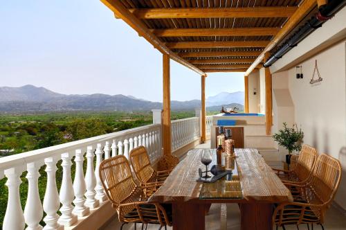 a wooden table and chairs on a balcony with mountains at Mylostassi Villas with Balcony Plunge Pool in Pláti
