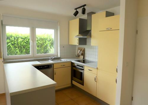 a kitchen with yellow cabinets and a sink and a window at Art & Nature Apartments in der Nähe FFM-Messe in Bad Vilbel