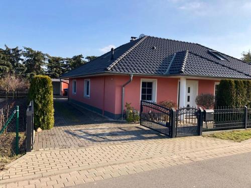 a pink house with a fence in front of it at Seeliebe mit Sauna und nur 50 mtr. bis zum Strand in Senftenberg
