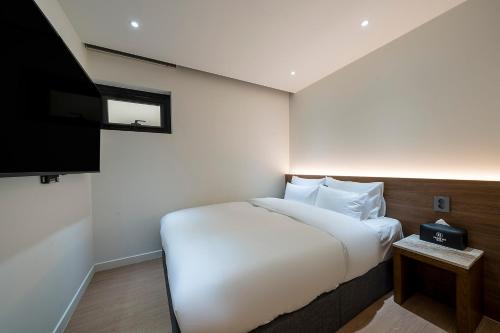 a bedroom with a bed and a flat screen tv at Brown Dot Hotel Pyeonghwa plaza in Mokpo