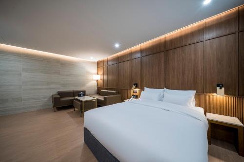 a bedroom with a large white bed and a couch at Brown Dot Hotel Pyeonghwa plaza in Mokpo