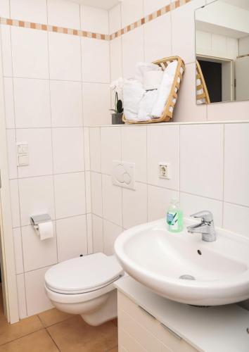 a white bathroom with a toilet and a sink at Art & Nature Apartments in der Nähe FFM-Messe in Bad Vilbel