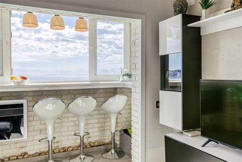 エンプリアブラバにあるAtic Beach D-Luxeの窓際のキッチン(白い椅子2脚付)