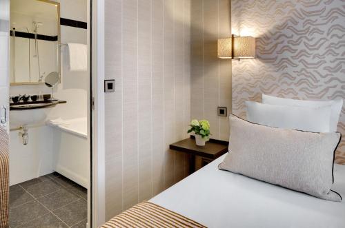パリにあるル セナのベッドとバスルーム付きのホテルルームです。