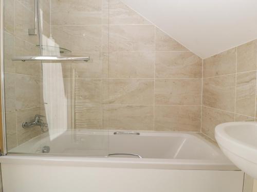 a bathroom with a bath tub and a sink at The Loft At Nordrach Lodge in Bristol