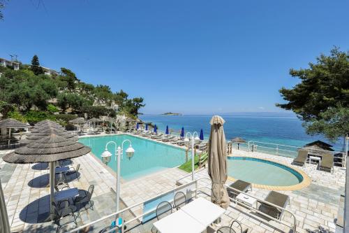 een zwembad met stoelen en parasols naast de oceaan bij Agali Hotel Paxos in Gaios
