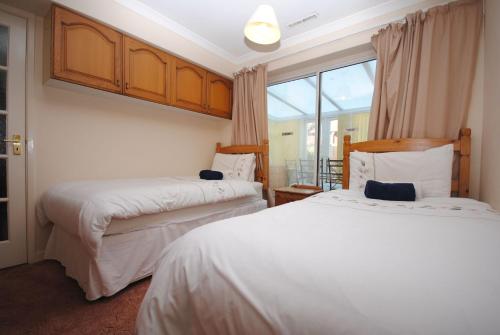 two beds in a room with a window at Lifeboat View, Selsey in Selsey