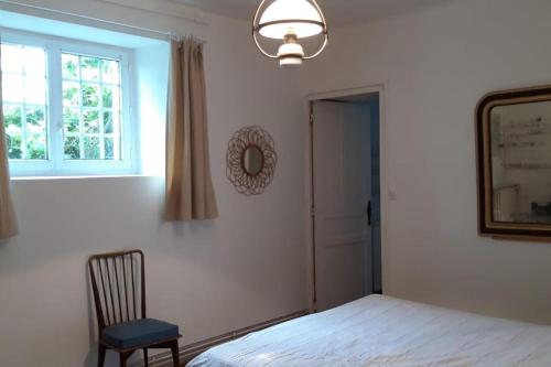 une chambre avec un lit, une fenêtre et une chaise dans l'établissement Bel appartement dans un magnifique domaine du XVIe, à Autouillet