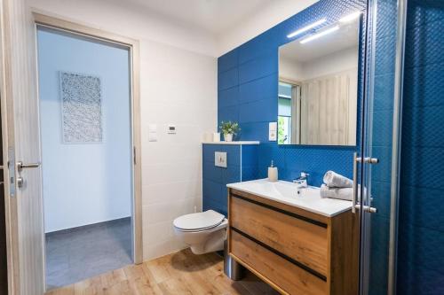 uma casa de banho azul com um WC e um lavatório em Lake27apartman em Szántód