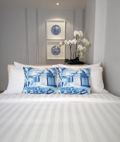 a bed with blue and white pillows and a vase with flowers at K Maison Boutique Hotel in Bangkok