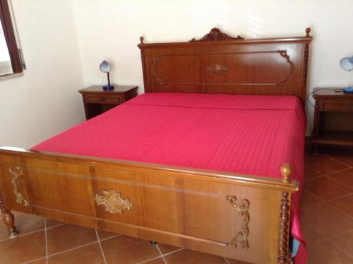 a bedroom with a wooden bed with a red bedspread at Favignana Vacanze in Favignana
