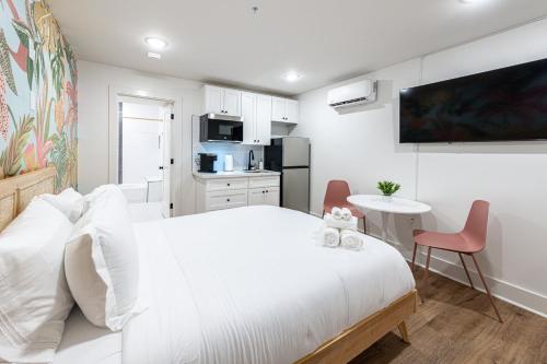 biała sypialnia z białym łóżkiem i stołem w obiekcie Pastel Tropics Studio Apartment w mieście Galveston