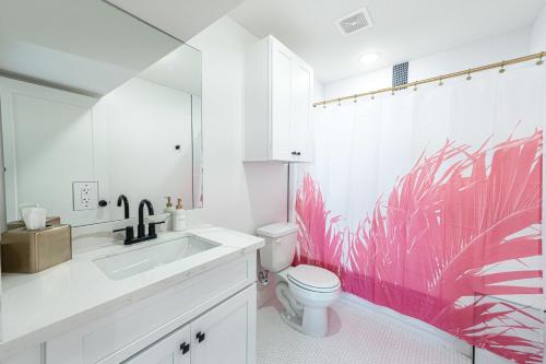 a bathroom with a toilet and a pink wallpaper at Pastel Tropics Studio Apartment in Galveston