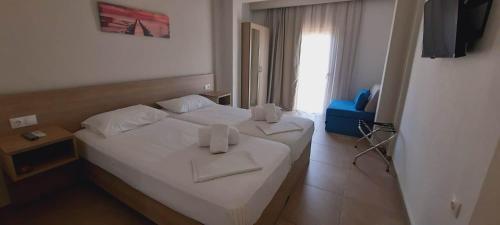 a bedroom with a white bed with towels on it at Lola's Hotel in Platanias