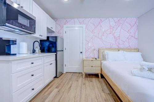 a small bedroom with a white bed and a kitchen at Pink Flamingo Studio Apartment in Galveston