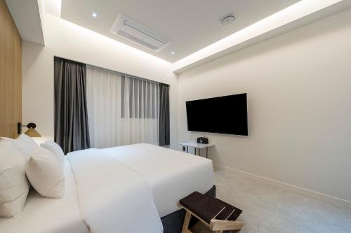 a bedroom with a white bed and a flat screen tv at Brown Dot Hotel Pyeonghwa plaza in Mokpo